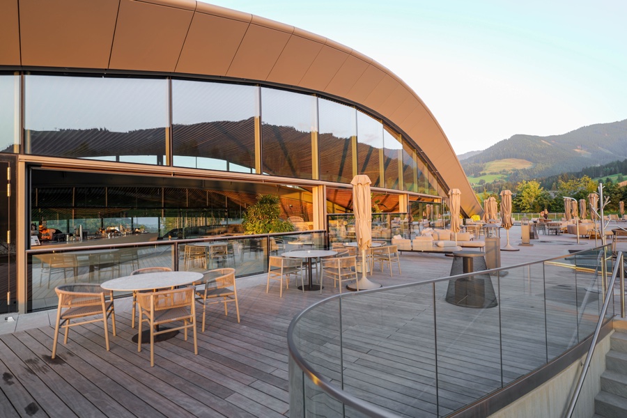 Terrasse am Atmosphere, die Glasfassade spiegelt die Berge